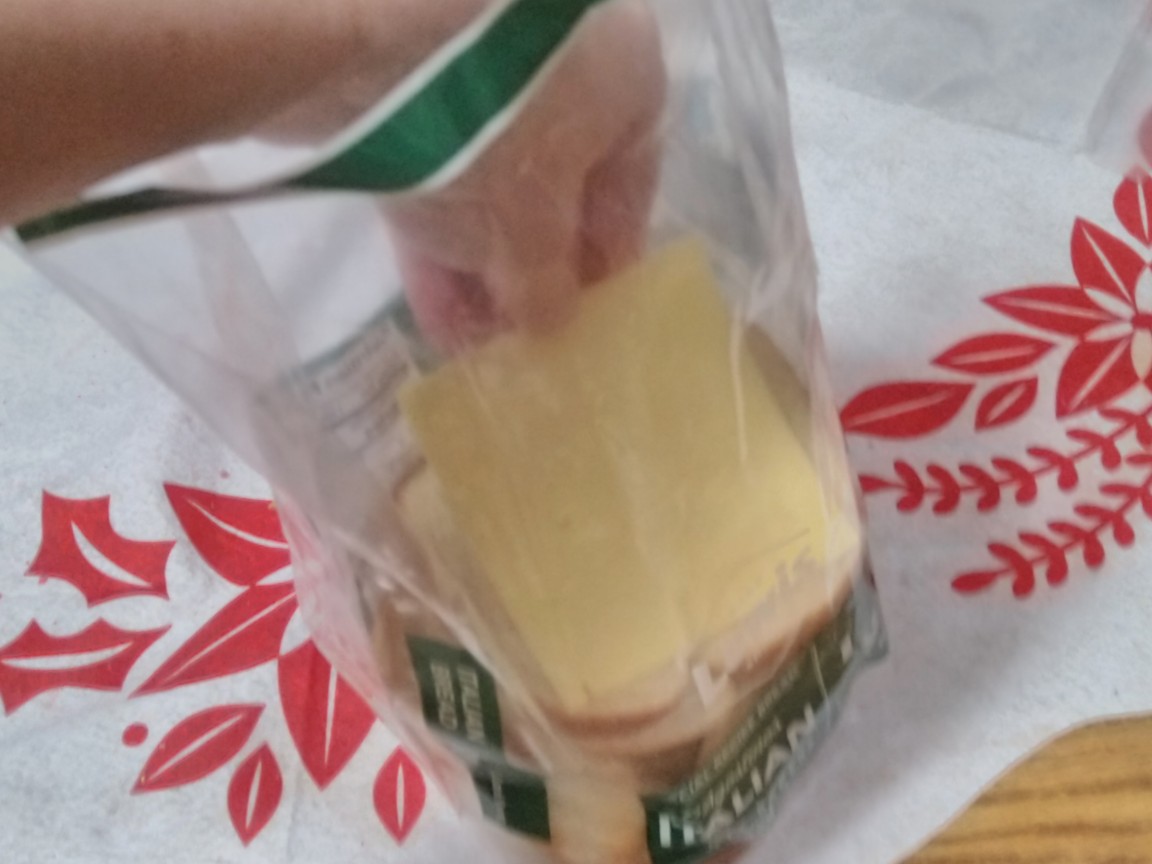A slice of cheese has been inserted into the bread's wrapper